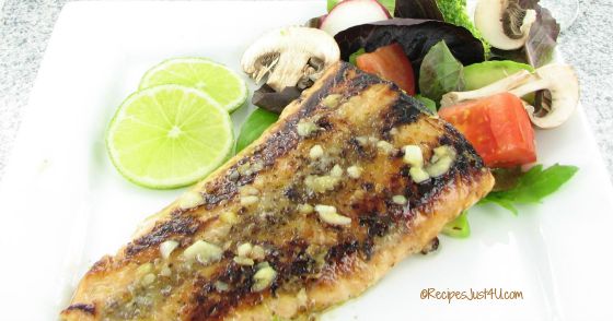 Honey glazed salmon with brown butter lime sauce and salad on a white plate.