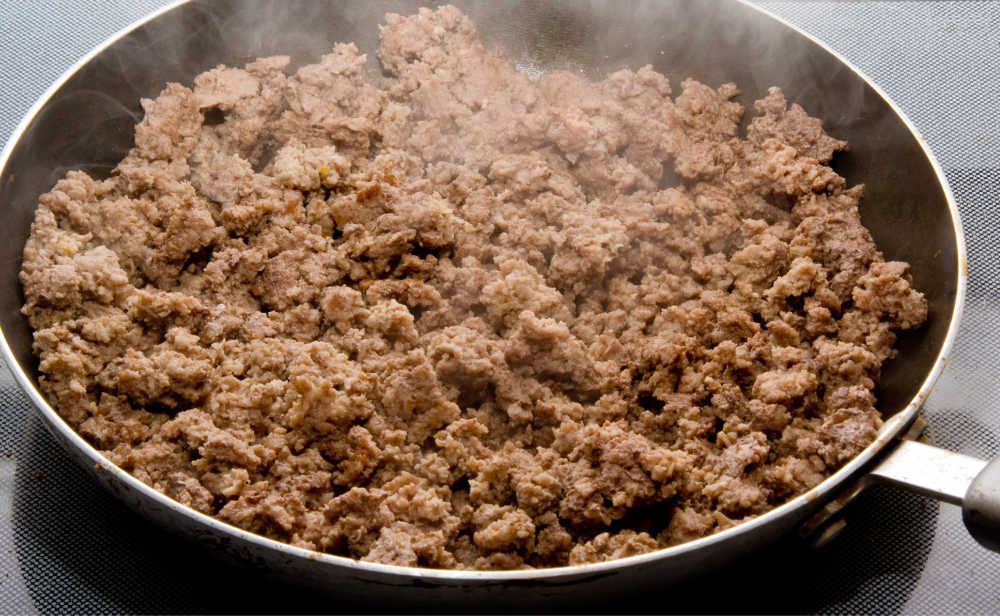 Cook the ground beef A pan on a stove with cooked ground beef in it.