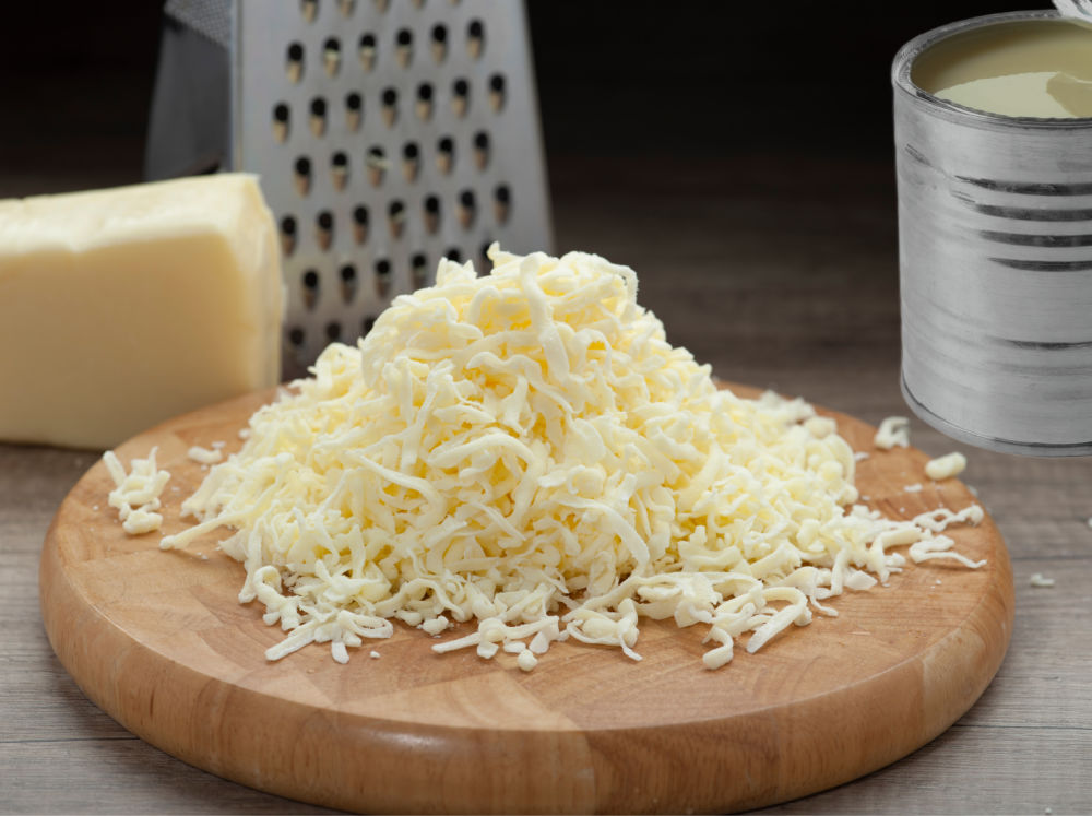 Add the cheese and evaporated milk. Shredded white American cheese on a chopping board next to a can of opened evaporated milk.