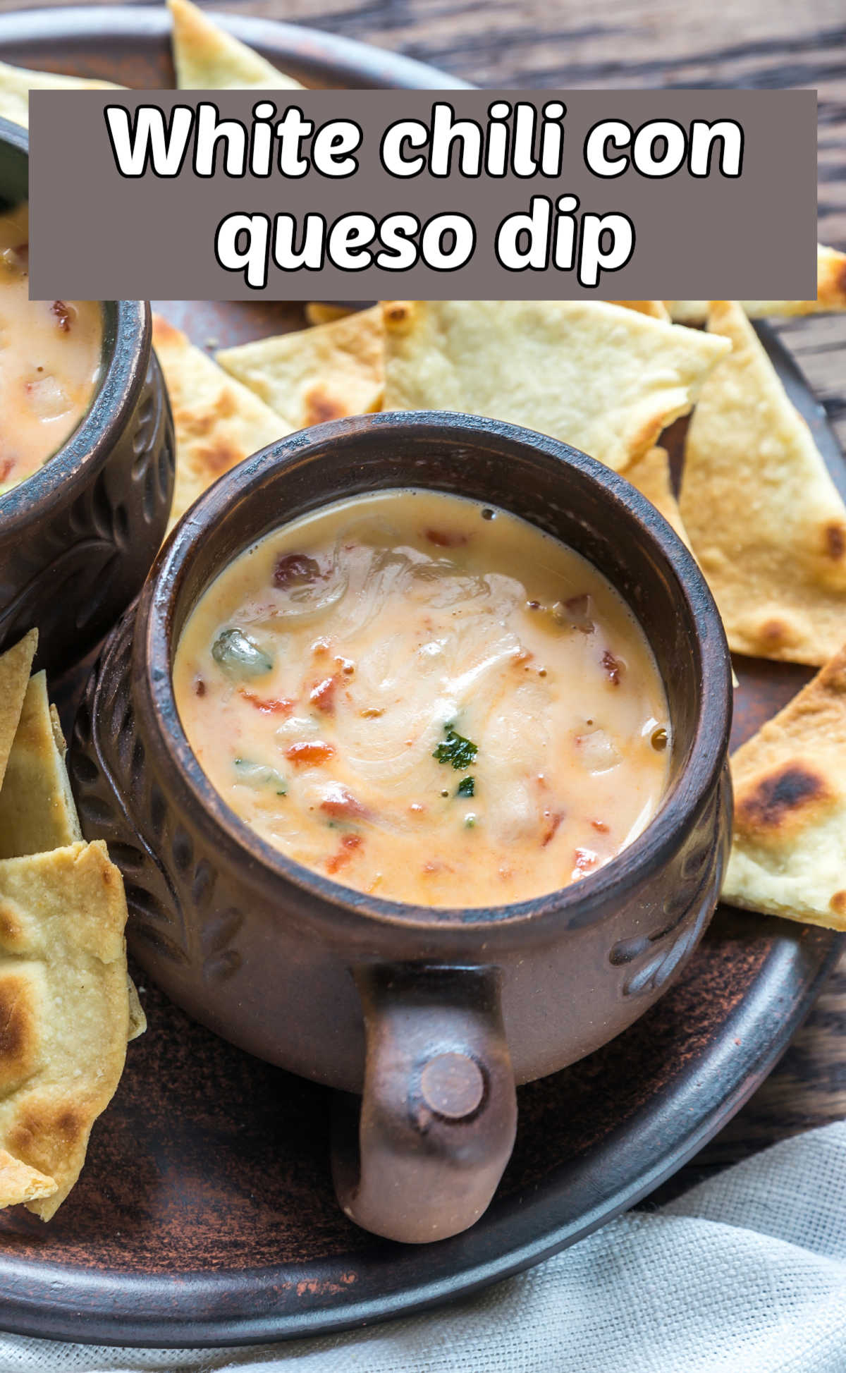 How to a Make White Chili Con Queso Dip Recipe Queso dip in a brown bowl surrounded by tortilla chips. Text rewads White chili con queso dip.