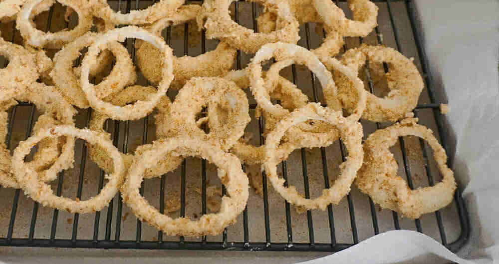 Baked onion rings cooling on a rack.