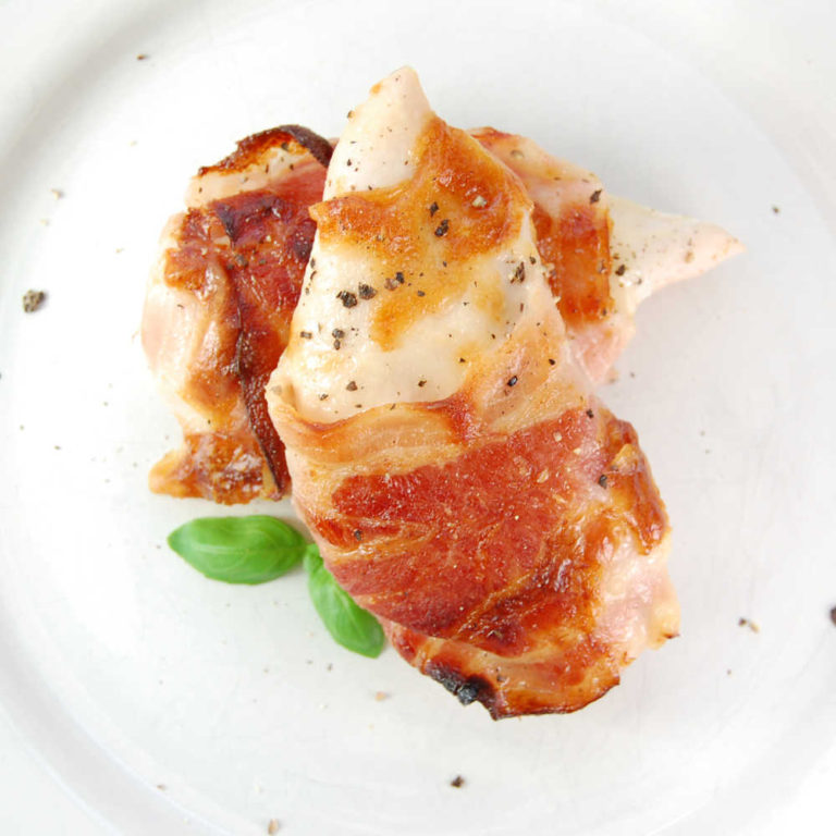Chicken breasts with a bacon wrapping on a white plate
