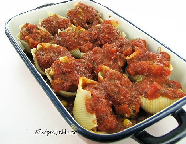 Easy Mexican pasta shells with ground beef topped with marinara sauce in a baking dish.