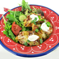 Taco stuffed pasta shells on a red and blue plate with salad.