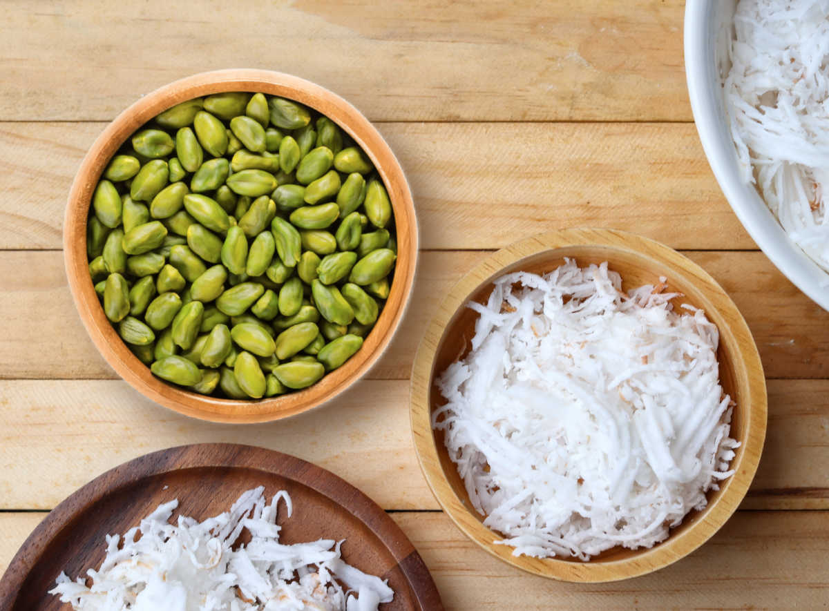 Pistachios and shredded coconut in wooden bowls.