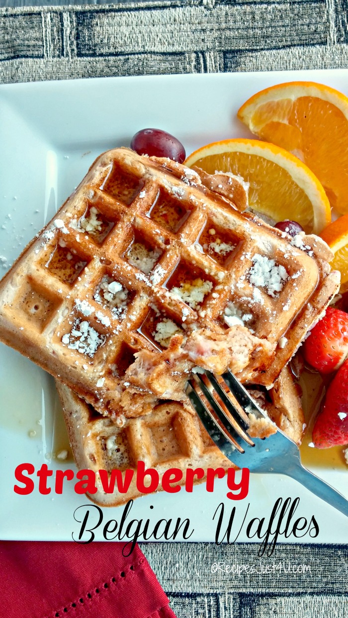 Waffles with oranges and strawberries on a plate with words Strawberry Belgian Waffles.