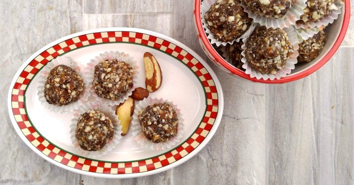 A plate with four coconut lemon energy bites, beside a bowl of more of these Whole30 energy balls.