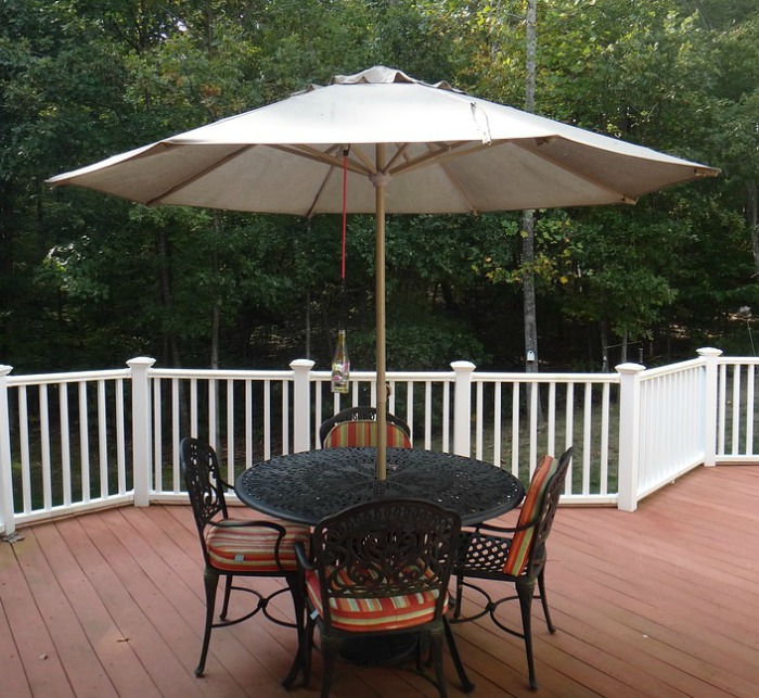 patio table and chairs with umbrella on a deck with a railing.