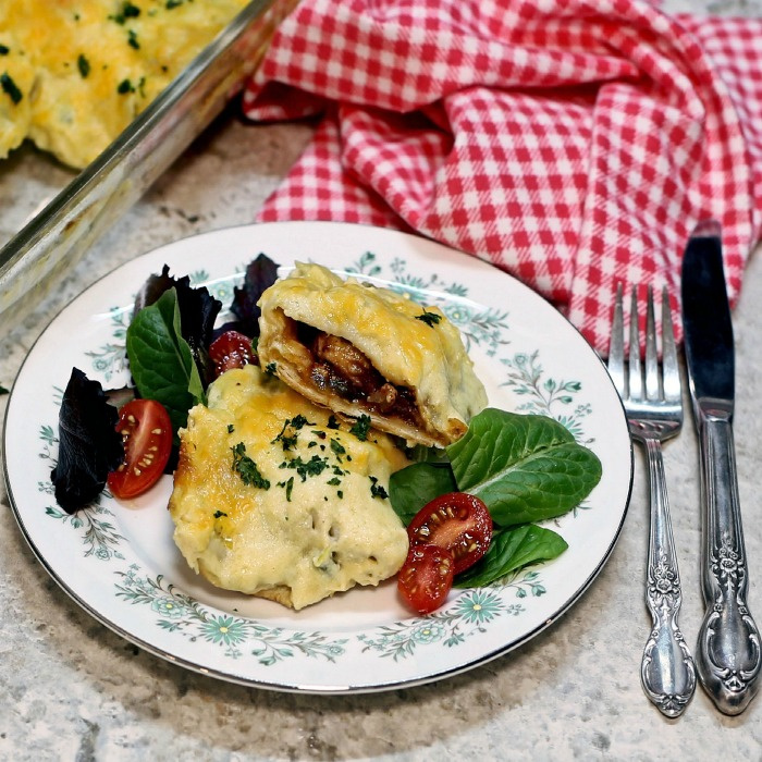 Creamy chicken enchiladas on a flowered plate with a small salad.