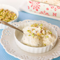 Homemade coconut pistachio ice cream in a white bowl with pistachios in the background.