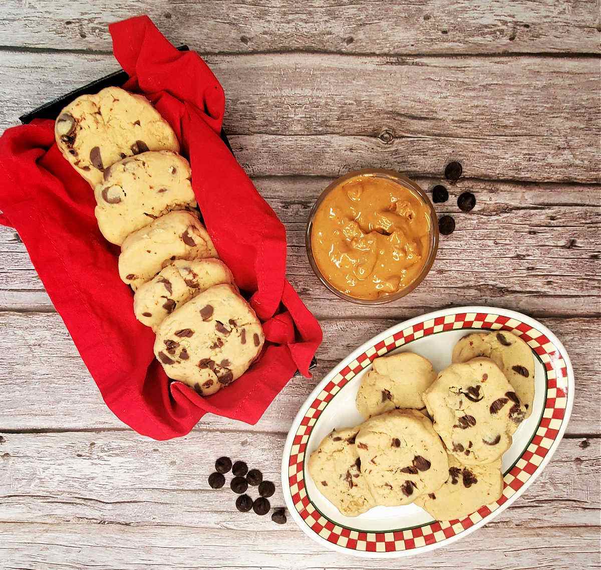 Cookies on a plate and in a red basket next to a bowl of peanut butter.