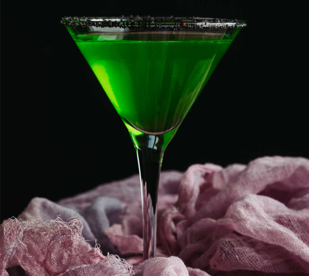 Halloween cocktail recipe: Green Halloween drink in a martini glass with a black rim.