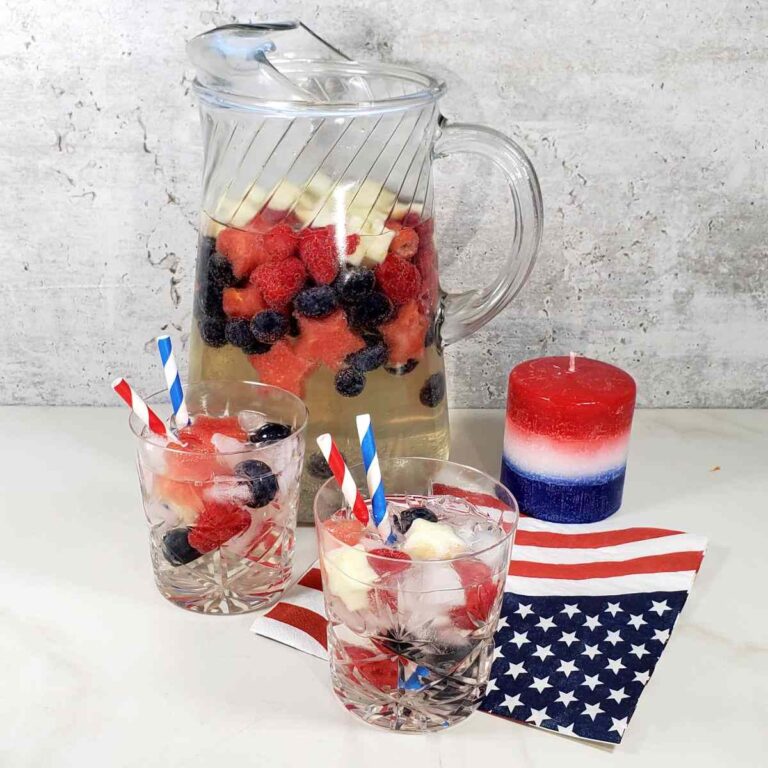 Picture with wine spritzers and glasses near a patriotic napkin and candle.
