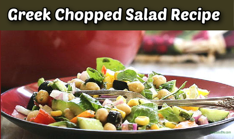 Greek chopped salad on a red plate next to a serving bowl.