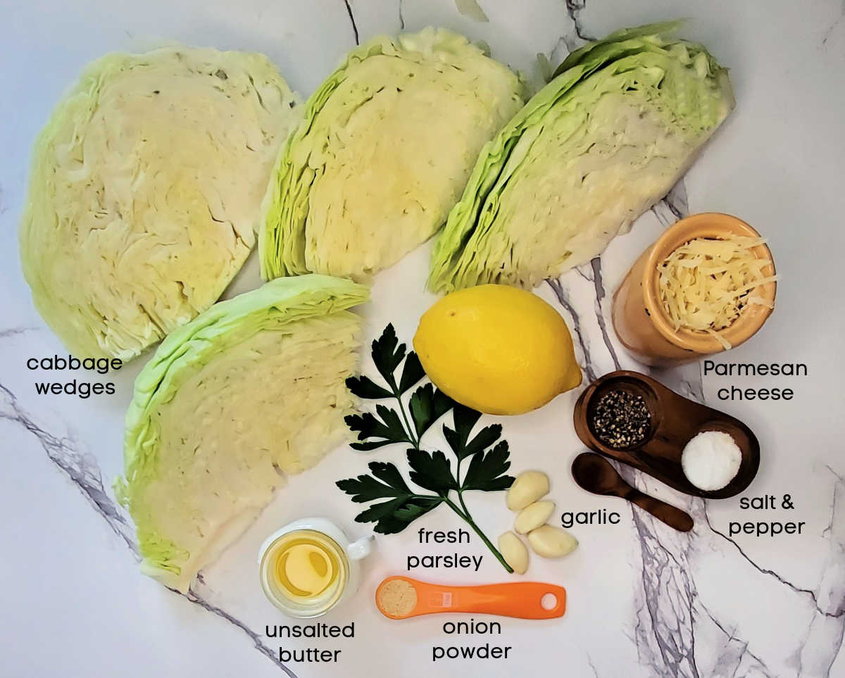 Cabbage wedges with lemon, parsley, salt, pepper, Parmesan cheese, butter and onion powder on a marble counter.