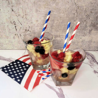 2 glasses of 4th of July sangria sitting on a flag napkin with red, white and blue striped straws.