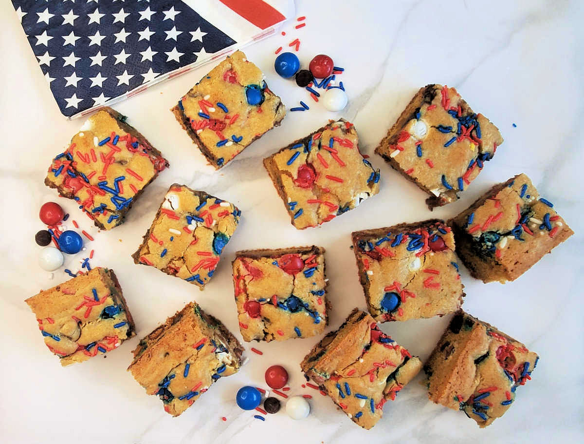 Patriotic cookie bars on parchment paper near a flag napkin and M&M candies.