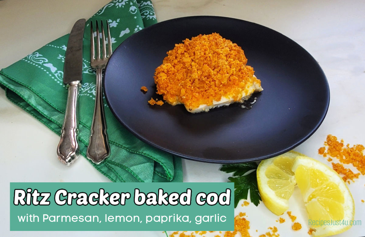 A black plate with crunchy fish near a green napkini, cutlery and slices of lemon and sprigs of parsley. Green text box reads Ritz cracker baked cod with Parmesan, lemon, paprika, garlic.