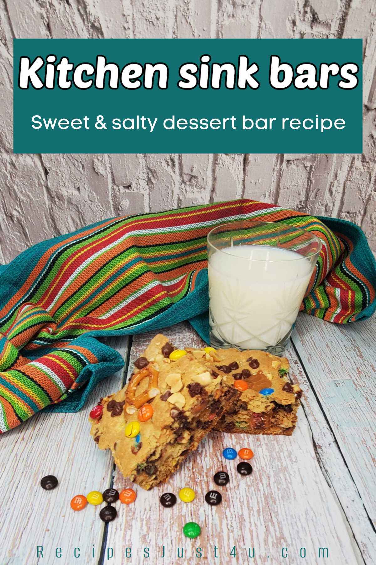 Two bars on a wooden counter next to a glass of milk, colorful towel and M & Ms. Teal text box reads Kitchen sink bars, sweet & salty dessert bar recipe.