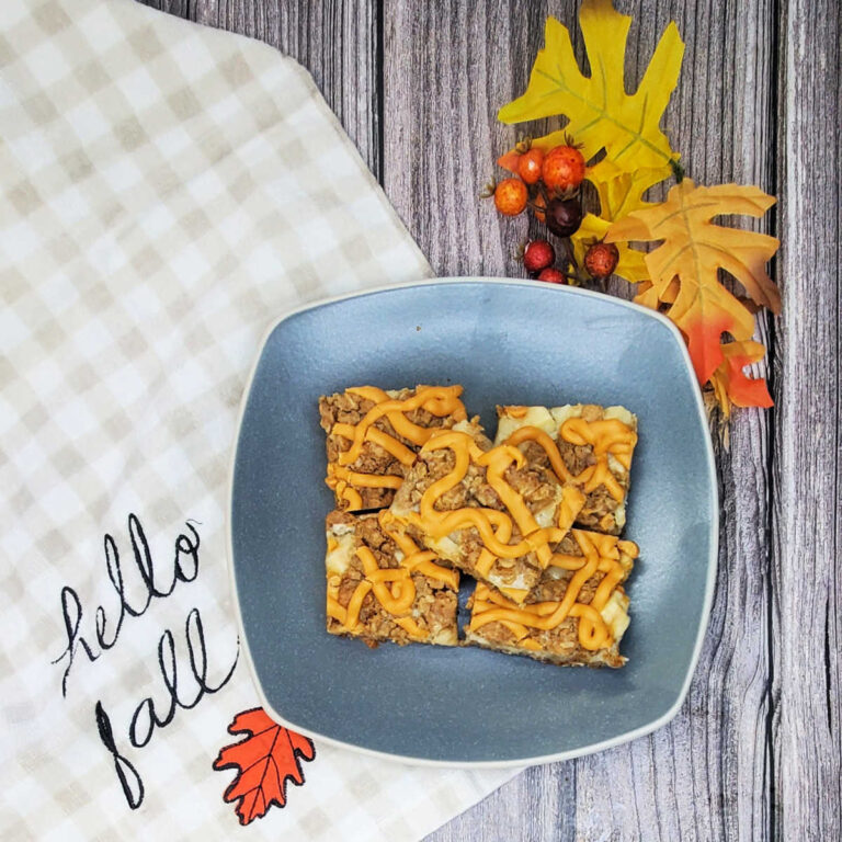 A grey plate with butterscotch bars on it siting on a Hello Fall towel and autumn leaves.