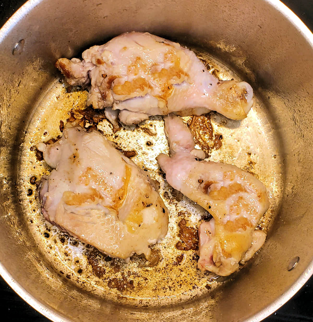 Sear the chicken pieces A large pot with seared chicken pieces in hot oil.