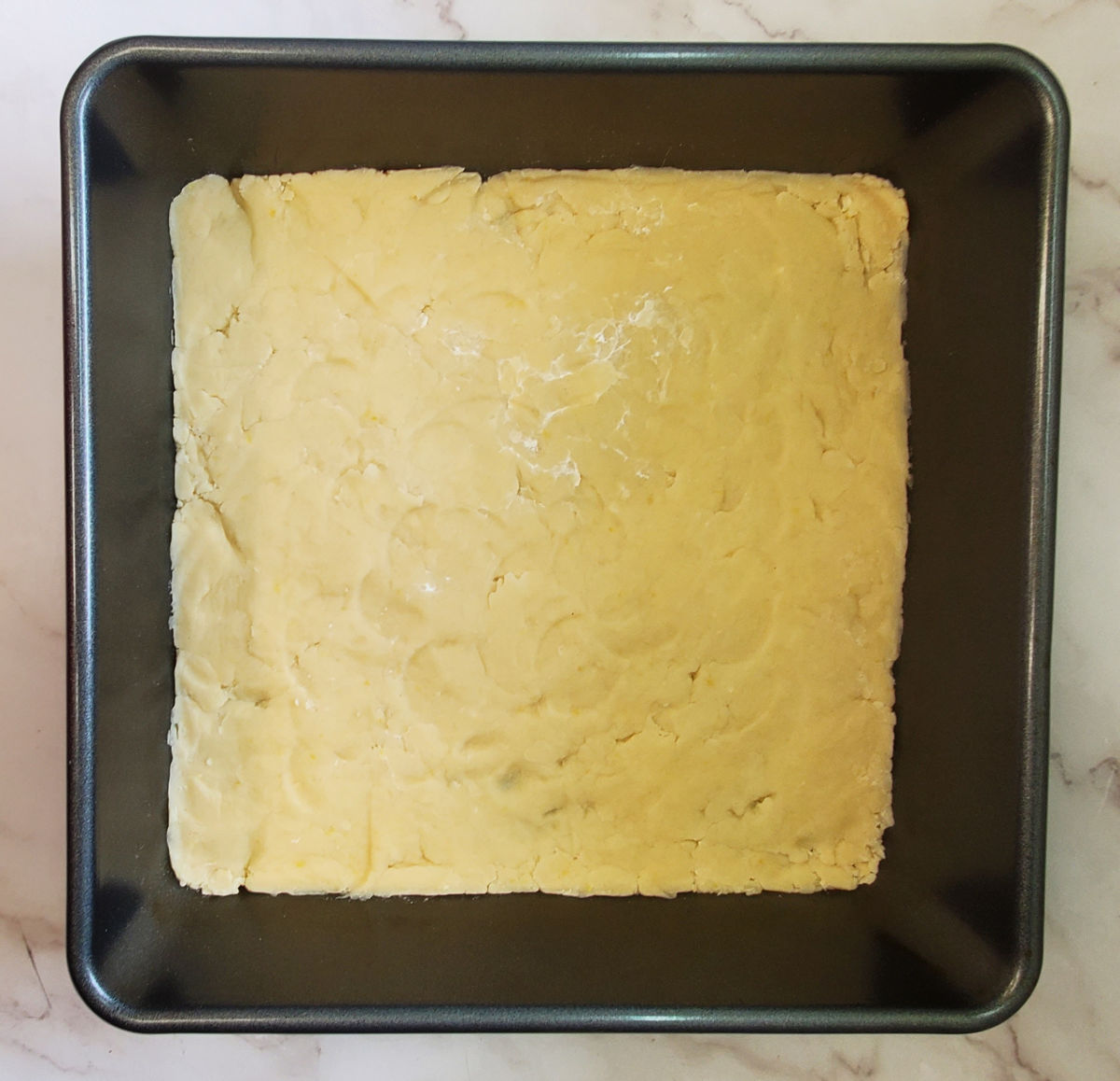 A baking pan containing the pressed down crumb crust for an easy lemons bars recipe.