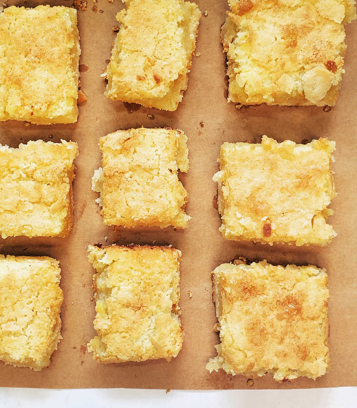 Lemon dessert bars cooling on a large piece of brown butcher's paper.