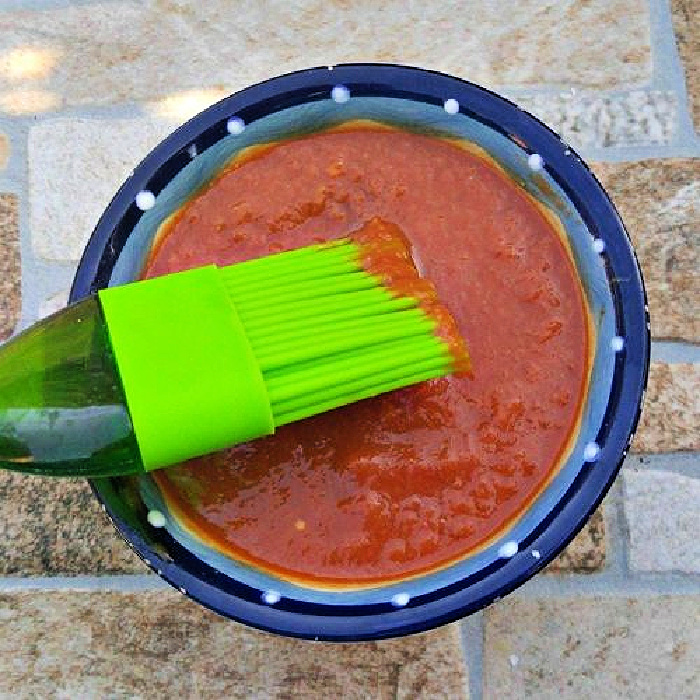 Sugar-free BBQ sauce in a blue bowl with a green silicone brush.