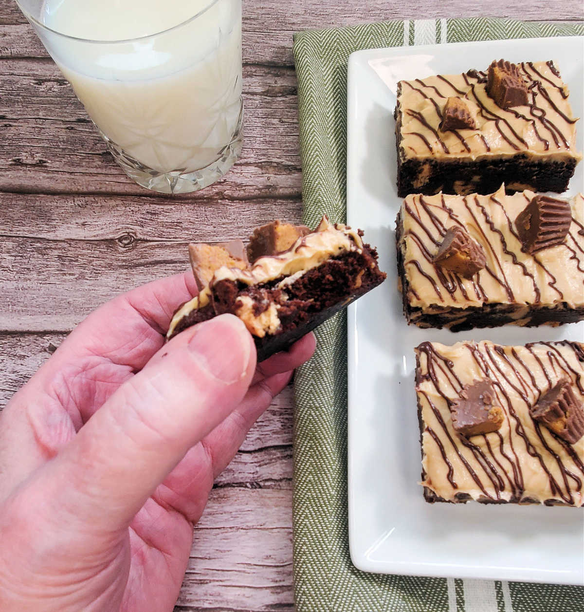 A hand holding a Reese's peanut butter brownie with a bite out of it.