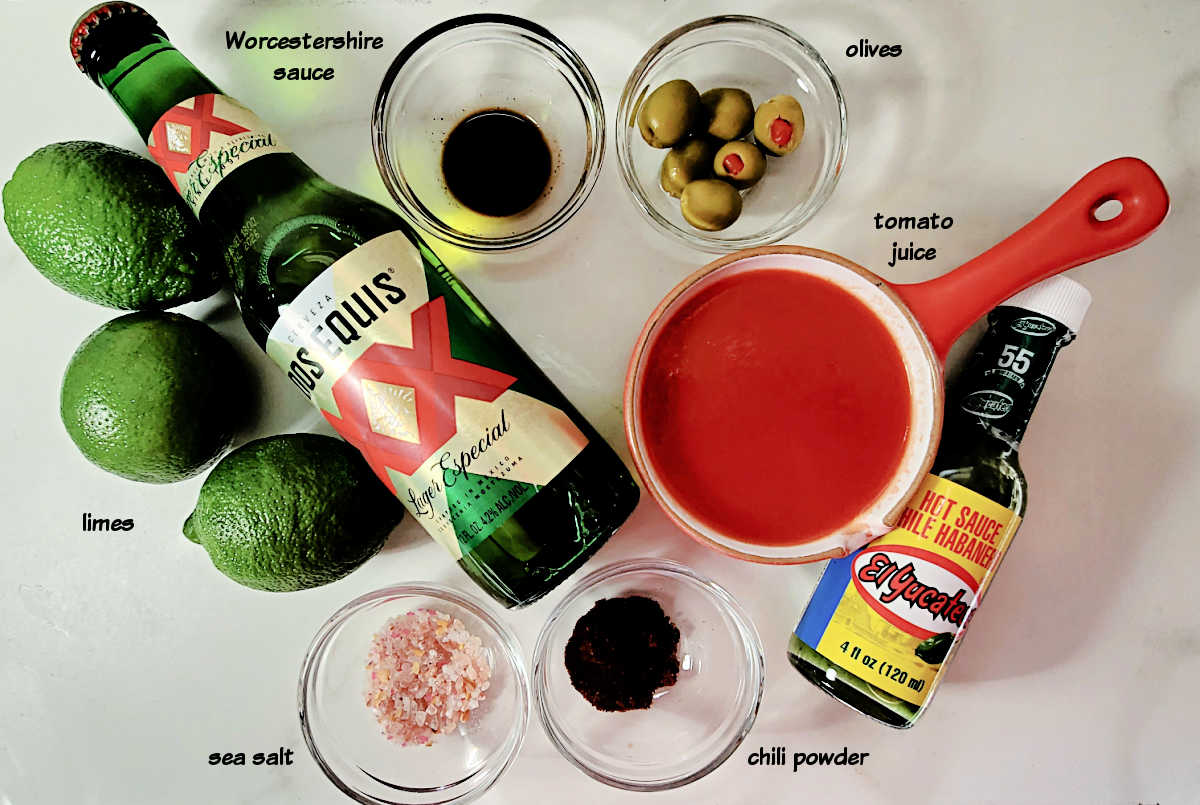 Ingredients for a Michelada recipe: Mexican beer, limes, tomato juice, hot sauce, Worcestershire sauce and olives.