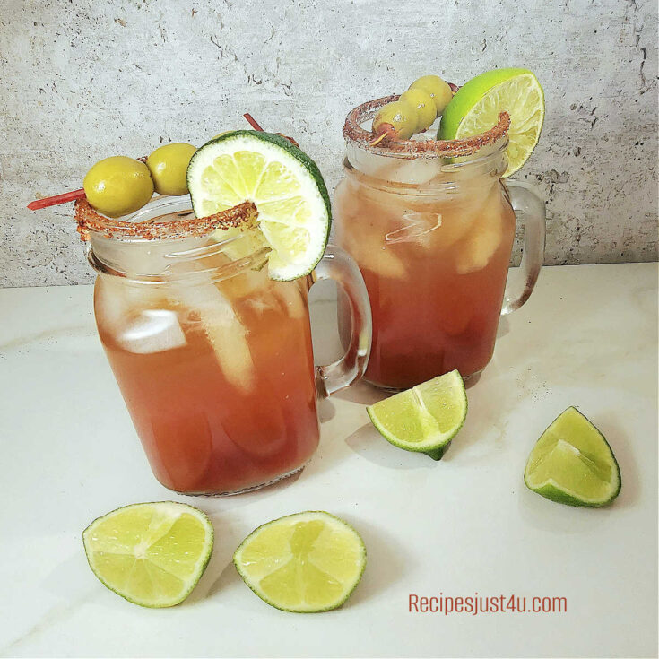 2 spicy Mexican beer cocktails in Mason jar mugs with olives and limes.