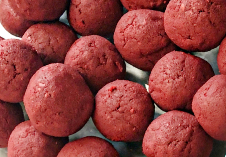 Red velvet cake balls with cream cheese in a glass pan.
