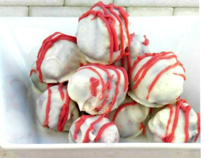 Red velvet cake truffles recipe in a white bowl on a marble counter.