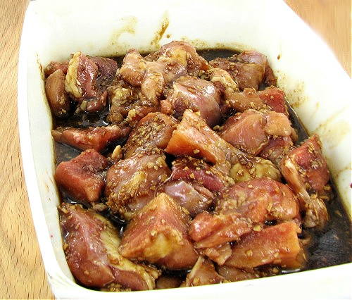 A bowl containing chicken thighs soaking up a Chinese marinade.