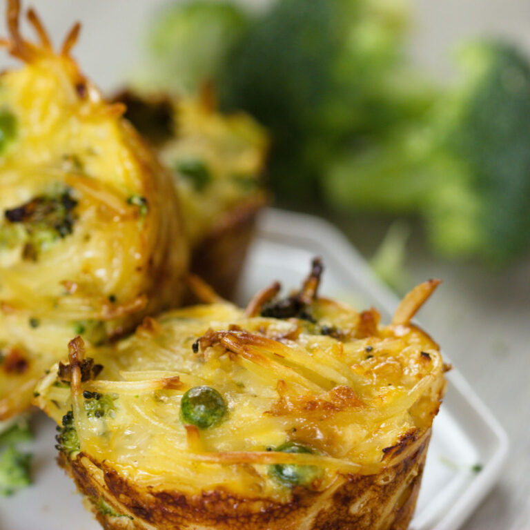 Egg and broccoli muffins on a white plate next to some broccoli florets.