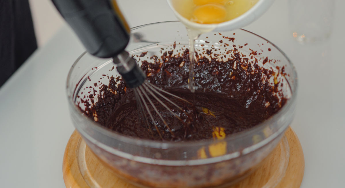Woman making baileys brownies batter, adding eggs stage.