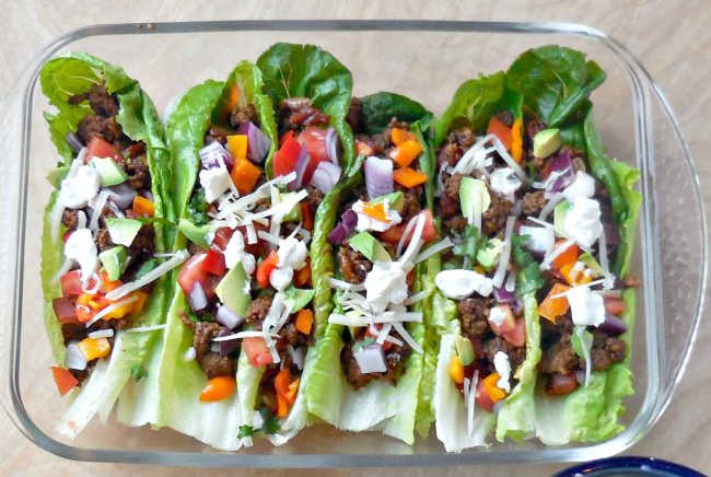 Beef taco lettuce wraps with peppers, cheese, sour cream and tomatoes.