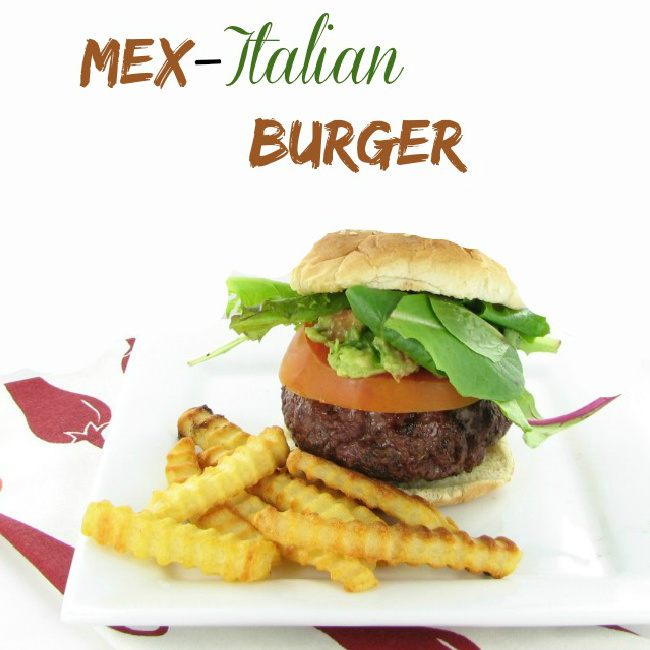 A Mexican Italian burger with lettuce and tomato on a white plate with French fries with a text overlay at the top that says Mex-Italian burger.